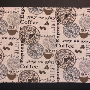 May include: A beige linen placemat with a repeating pattern of coffee cups, coffee beans, and the words "Espresso", "Latte", "Cappuccino", and "Coffee".