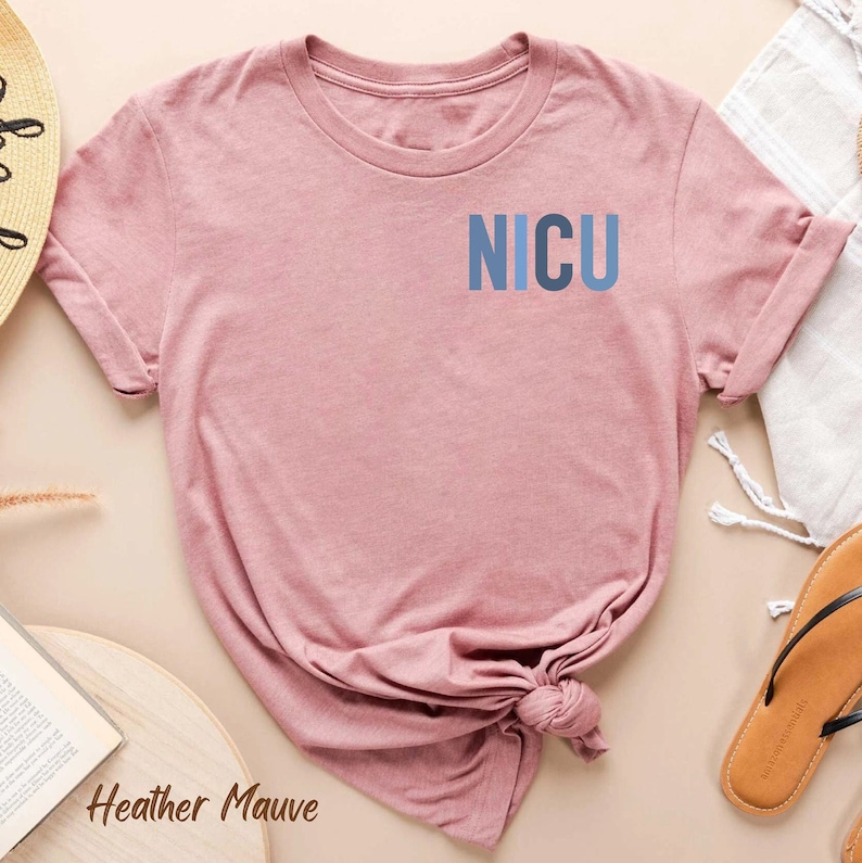 May include: A heather mauve t-shirt with the word "NICU" printed in blue on the front.