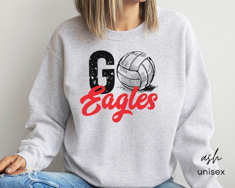 以下が含まれることがあります： グレーのトレーナーに、赤と黒の文字で「Go Eagles」と書かれています。テキストの上に、バレーボールの白黒のイラストがあります。