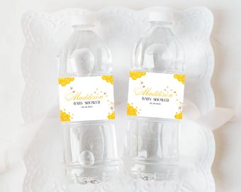 May include: Two clear plastic water bottles with yellow and white labels that say "Madisson Baby Shower 02.28.2023". The labels have a honeycomb pattern and small bee illustrations.