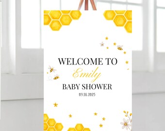 May include: Welcome to Emily's Baby Shower sign with a white background and yellow honeycomb and bee illustrations. The date of the shower is 03 28 2025.