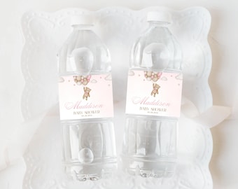 May include: Two clear plastic water bottles with pink and white labels. The labels feature a cartoon teddy bear holding pink balloons and the text "Madisson Baby Shower".