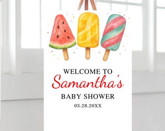 May include: A white sign on a wooden easel with watercolour illustrations of ice lollies. The sign reads "WELCOME TO Samantha's BABY SHOWER 03.28.20XX" in red and black text. The ice lollies are watermelon, yellow, and red and blue.