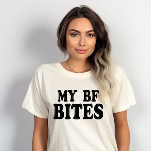 May include: A white t-shirt with black text that reads "MY BF BITES".