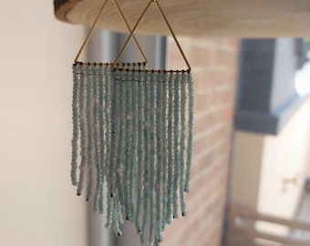 May include: A pair of gold triangle earrings with a fringe of light blue beads.
