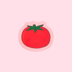 Puede incluir: Un tomate rojo con un tallo verde y una cara de dibujos animados, sobre un fondo rosa.