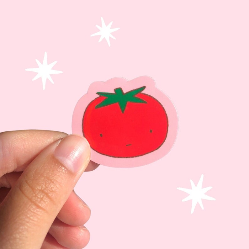 Puede incluir: Una pegatina de tomate rojo con un tallo verde y una linda cara de dibujos animados. La pegatina est&aacute; sobre un fondo rosa con estrellas blancas.