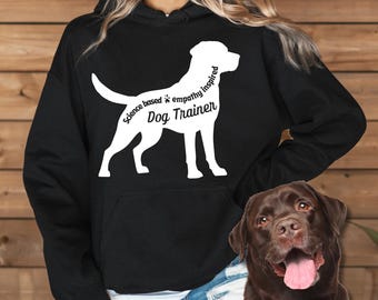 May include: Black hoodie with a white silhouette of a Labrador Retriever. The silhouette is outlined with the text "Science based * empathy inspired Dog Trainer".