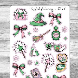 May include: A sheet of stickers featuring witch-themed illustrations. The stickers include a witch hat, purse, bows, a broom, a potion bottle, heart-shaped sunglasses, a compact, a wand, a flip phone, and a bracelet. The color scheme is pink, green, and white.