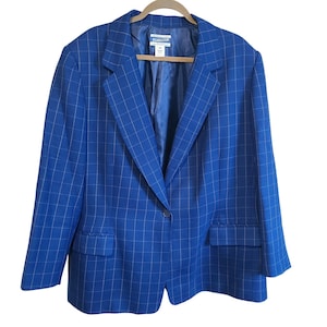 Puede incluir: Un blazer azul con un patrón de cuadrícula. El blazer tiene solapas con muescas, dos bolsillos delanteros y un cierre de un solo botón. El forro interior es azul liso. La marca "Pendleton" es visible en una etiqueta.