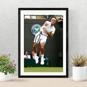 May include: A framed photograph of a tennis player in mid-air, swinging a tennis racket. The player is wearing a white shirt and shorts, and is on a green tennis court.