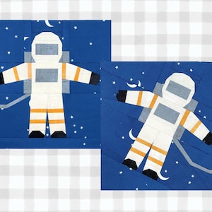 Op de afbeelding: Twee stoffen vierkanten met astronauten. Elke astronaut is afgebeeld in een wit ruimtepak met oranje strepen en zwarte handschoenen en laarzen, tegen een donkerblauwe sterrenhemel. De vierkanten staan op een geruite achtergrond.