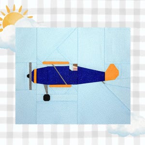 May include: A fabric quilt block featuring a dark blue airplane with orange wings and tail, set against a light blue background with white dots. The design includes a yellow sun and white clouds in the corner, all on a white and gray checkered base.