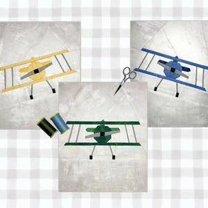 Puede incluir: Tres cuadrados de tela con fondo blanco y un solo diseño de avión en cada uno. Los aviones son amarillo, azul y verde. Los cuadrados están rodeados por un patrón de cuadros blancos y grises.