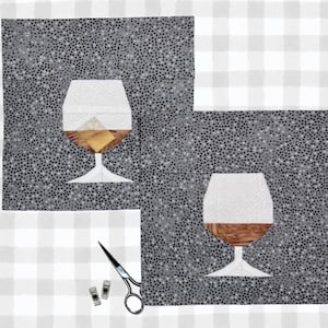 May include: Two fabric squares with a gray dotted pattern feature appliqued images of a brandy snifter. The snifters are white, brown, and tan. A pair of scissors and two small clips are in the lower right corner.