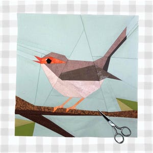 Puede incluir: Un pájaro de patchwork geométrico con pico y patas naranjas, posado en una rama marrón sobre un fondo azul claro. El pájaro está hecho de telas grises, marrones y blancas. Unas tijeras descansan debajo de la rama.