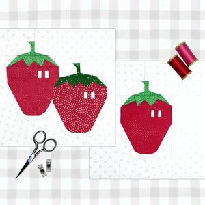 Peut inclure: Deux formes de fraises en tissu rouge et vert sur des carrés de tissu blanc. Les fraises ont des points blancs et des cercles blancs pour les graines. Il y a deux bobines de fil rouge et deux pinces en tissu sur le tissu blanc.