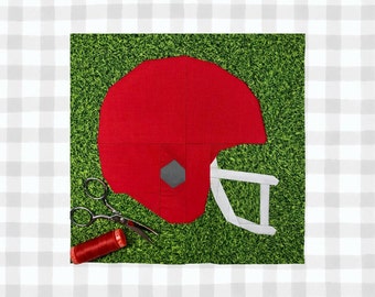 May include: A red and white football helmet applique on a green fabric background. The helmet is surrounded by scissors and a spool of red thread.