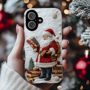 May include: A white phone case with a festive design featuring Santa Claus holding a stack of books. The case has a white background with a textured surface and a red and white Santa Claus figure in the center. The Santa Claus figure is wearing a red suit with white trim and a white beard. He is holding a stack of books in his left hand and a small red bag in his right hand. The case has a cutout for the phone's camera lens.
