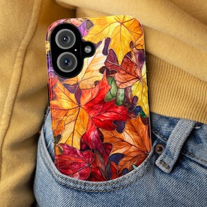 May include: A phone case with a colorful autumn leaf design. The case features a variety of red, orange, yellow, and green leaves.