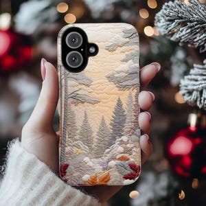 May include: A phone case featuring a detailed landscape design with trees, clouds, and a warm-toned sky. The case has a textured appearance, with a winter forest scene in shades of gray, brown, and orange. The phone case is designed to fit a smartphone.