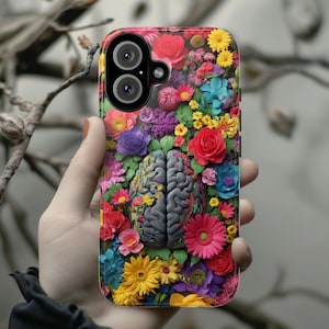 May include: A smartphone case featuring a vibrant floral design with a gray brain graphic. The case is covered in colorful flowers, including red roses, yellow daisies, and purple blooms. The phone case has a dual-lens camera.