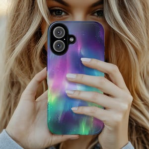 Puede incluir: Una funda para tel&eacute;fono con un dise&ntilde;o de aurora boreal colorido. La funda est&aacute; hecha de un material transparente y tiene un borde negro. La aurora boreal es una vibrante muestra de colores verdes, morados y rosas.