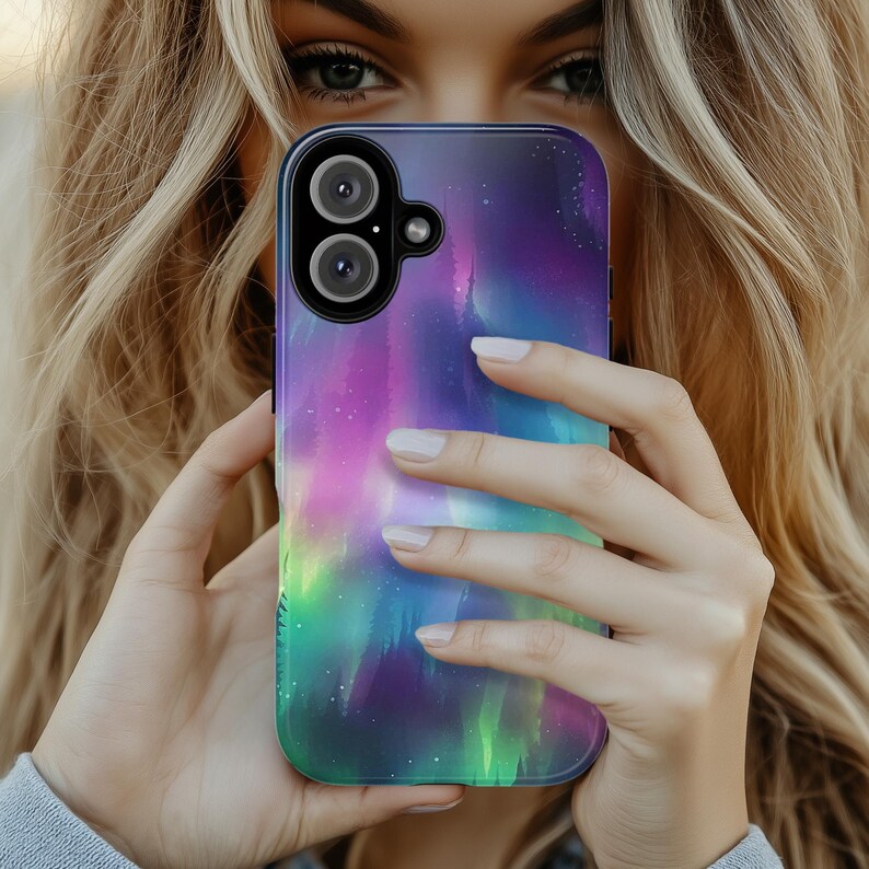 Puede incluir: Una funda para tel&eacute;fono con un dise&ntilde;o de aurora boreal colorido. La funda est&aacute; hecha de un material transparente y tiene un borde negro. La aurora boreal es una vibrante muestra de colores verdes, morados y rosas.