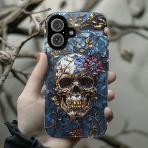 May include: A phone case with a blue, gold, and white skull design. The skull is surrounded by flowers and intricate patterns.