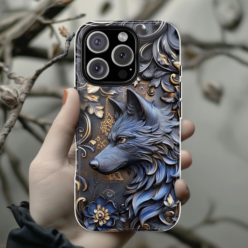 May include: A black phone case with a detailed design of a wolf's head with blue and gold accents. The case has a camera lens cutout and a decorative pattern.