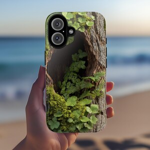 May include: A phone case with a green and brown design featuring a tree trunk with a hole and green foliage growing inside.