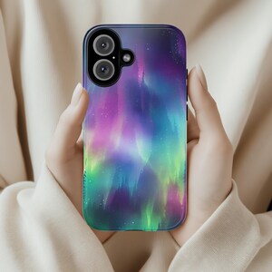 Puede incluir: Una funda para tel&eacute;fono con un dise&ntilde;o de aurora boreal colorido. La funda es negra y tiene una parte posterior transparente para mostrar el dise&ntilde;o. La aurora boreal es una mezcla vibrante de morado, verde, azul y rosa.