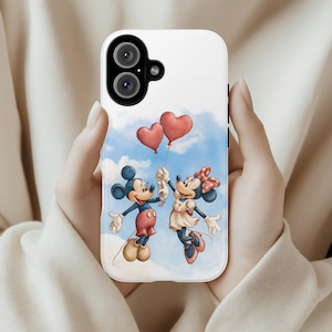 May include: White phone case with a cartoon illustration of Mickey and Minnie Mouse. They are holding red heart-shaped balloons against a blue sky. Mickey wears red shorts and yellow shoes, Minnie a dress and bow. The case has a dual-camera cutout.