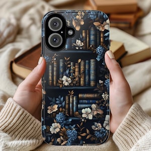 May include: A phone case with a dark blue background featuring a bookshelf filled with books and floral accents. The books are in shades of blue, gold, and brown. The flowers are in shades of blue, white, and gold.
