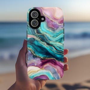 May include: A smartphone case with a colorful abstract design. The case features a swirling pattern of teal, purple, pink, and gold, resembling marble or agate. The case has a camera cutout and side buttons.