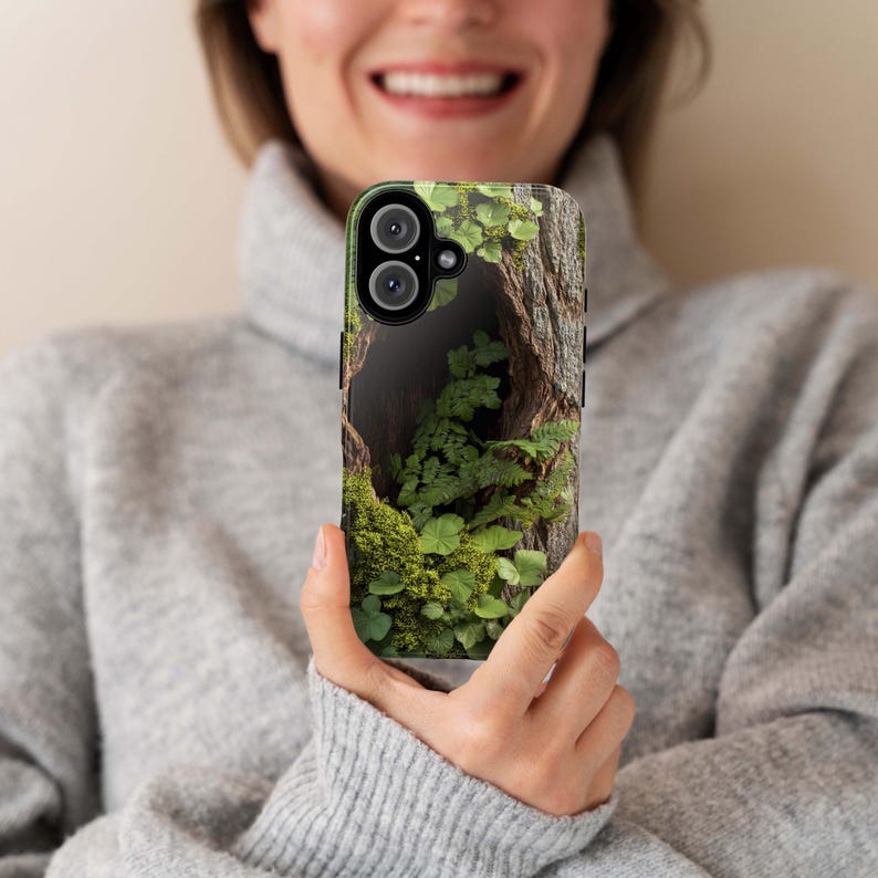 May include: A phone case with a green and brown nature scene. The case features a close-up of a tree trunk with a hole filled with moss and ferns.