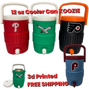 May include: A selection of 12 oz Cooler Can Koozies in red, green, black, and blue. Each koozie displays a team logo and has a white handle. The koozies have a tap for dispensing drinks. The text "3d Printed" is visible.