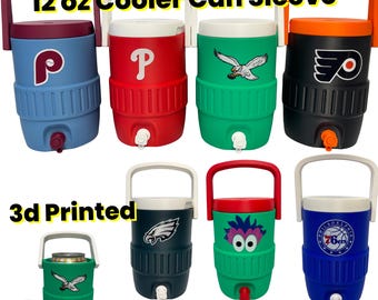 May include: A collection of 3D printed 12 oz cooler can sleeves shaped like beverage jugs with handles and spouts. The sleeves feature various sports team logos and colors, including red, blue, green, black, and white, with one showing a cartoon face.