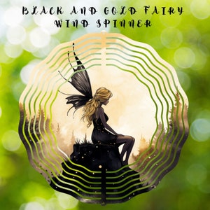 May include: Black and gold wind spinner featuring a fairy with black wings sitting on a rock. The fairy has long blonde hair and is wearing a black dress. The background is a blurred image of a forest.