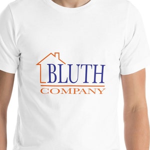 May include: White t-shirt with a blue and orange logo that says "Bluth Company" and features a house outline.