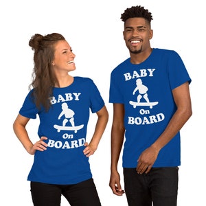 Peut inclure: Deux personnes portant des t-shirts bleu royal avec du texte blanc et un graphique d'un bébé sur une planche à roulettes. Le texte sur les t-shirts est "Baby on Board".