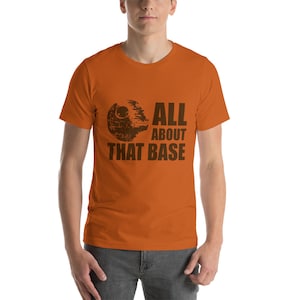 Peut inclure: T-shirt orange avec un graphique brun de l'Étoile de la Mort de Star Wars et le texte "All About That Base".