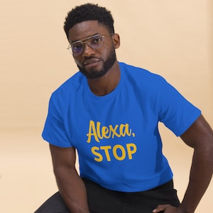 May include: A man wearing a royal blue t-shirt with the text "Alexa, STOP" in yellow lettering.