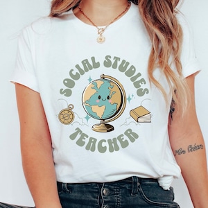 May include: White t-shirt with a graphic of a globe with a smiling face, surrounded by a circle that says "Social Studies Teacher" in green letters.