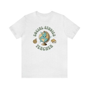 May include: White t-shirt with a green circle graphic that says "Social Studies Teacher" with a cartoon globe, compass, and book.