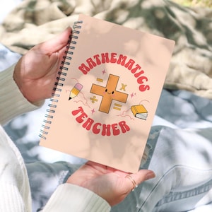 May include: A pink spiral notebook with the text "Mathematics Teacher" in a retro font. A cartoon plus sign with a smiling face is in the center of the notebook.