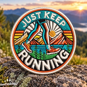 May include: A circular embroidered patch featuring a stylised graphic of legs running against a mountain landscape. The text JUST KEEP RUNNING is stitched in white. The design includes vibrant orange, teal, yellow, and green thread colours.