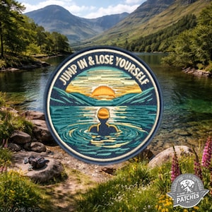 Può includere: Toppa rotonda ricamata con la scritta "JUMP IN & LOSE YOURSELF". Il disegno raffigura una persona che nuota in un lago al tramonto, con uno sfondo di montagne e acqua. La toppa ha un bordo blu.