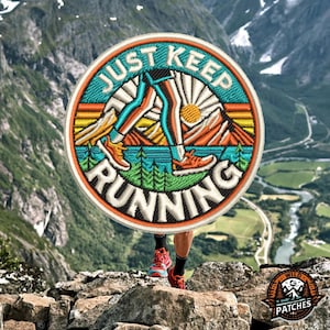 Puede incluir: Un parche redondo bordado con un diseño retro que presenta a una persona corriendo con montañas y un sol en el fondo. El texto "Just Keep Running" está escrito alrededor del borde del parche.