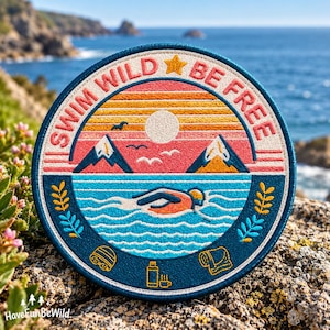 May include: A circular embroidered patch featuring a sunset over mountains and a swimmer in blue water. The text SWIM WILD BE FREE is arched at the top with a yellow star. Below the water, icons of a swim cap, a thermos, and a towel are depicted.
